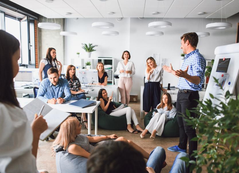 Vergadering Een groep mensen die op kantoor samenzitten voor een vergadering of presentatie van iemand.